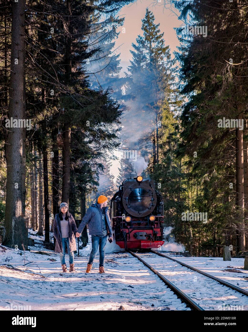 Paar Männer und Frauen wandern im Harz Nationalpark Deutschland, Dampfzug auf dem Weg nach Brocken durch die Winterlandschaft, berühmte Dampfzug durch den Winterberg. Brocken, Harz Deutschland Stockfoto