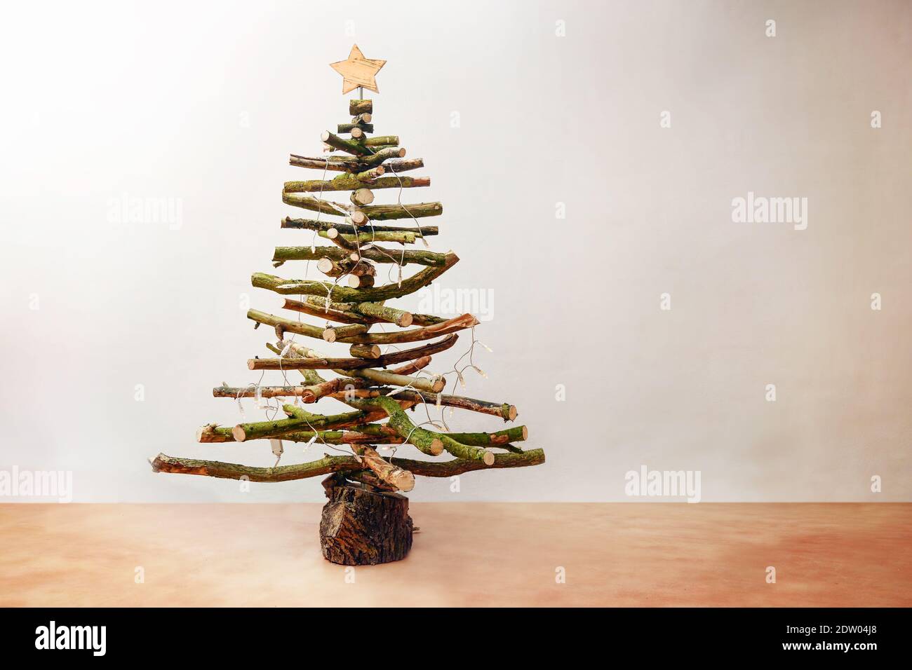 Rustikaler Weihnachtsbaum aus rohem Holz Äste mit Lichterketten und einem Stern, hausgemachte nachhaltige und umweltfreundliche Alternative für die holi dekoriert Stockfoto