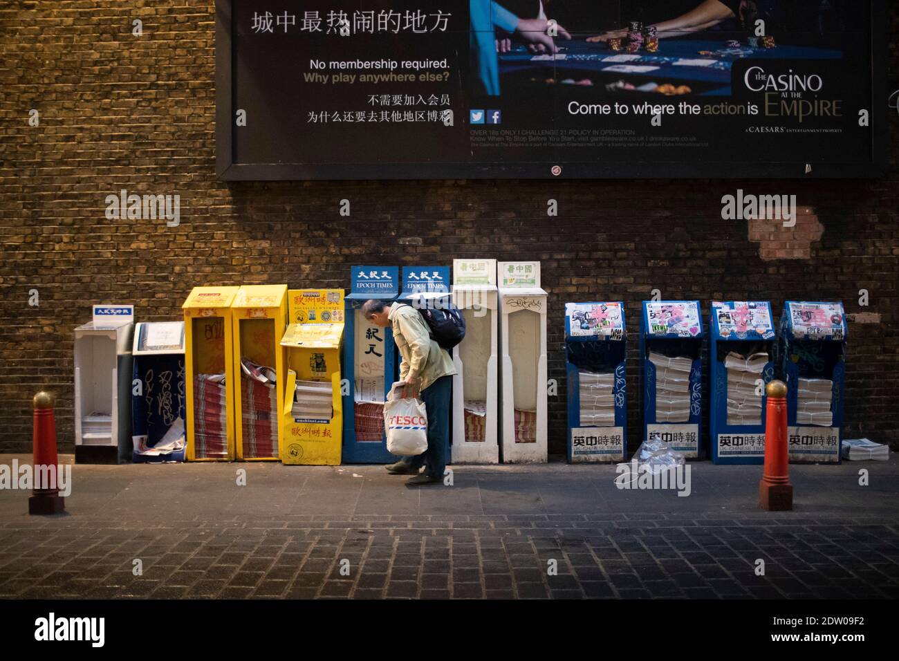 Ein Mann holt eine kostenlose Zeitung in Londons Chinatown ab Stockfoto