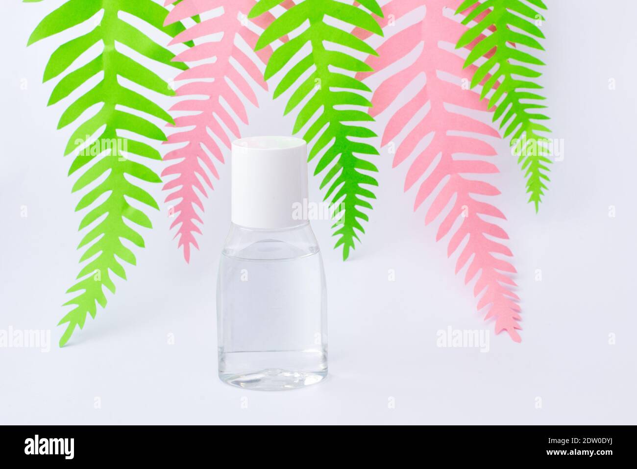 Medizinisches Öl auf weißem Hintergrund mit Papier grün und rosa Palmblätter Stockfoto