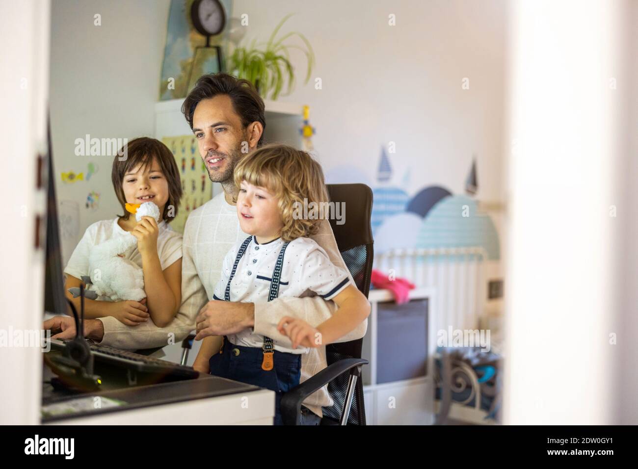 Vater versucht, von zu Hause aus mit seinen Kindern zu arbeiten Stockfoto