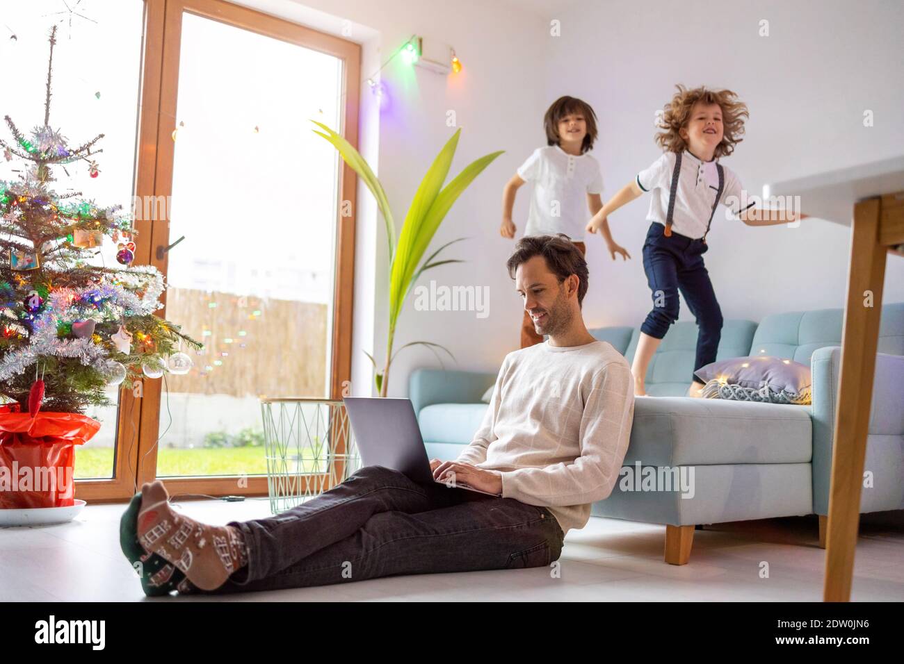 Vater versucht, von zu Hause aus mit seinen Kindern zu arbeiten Stockfoto