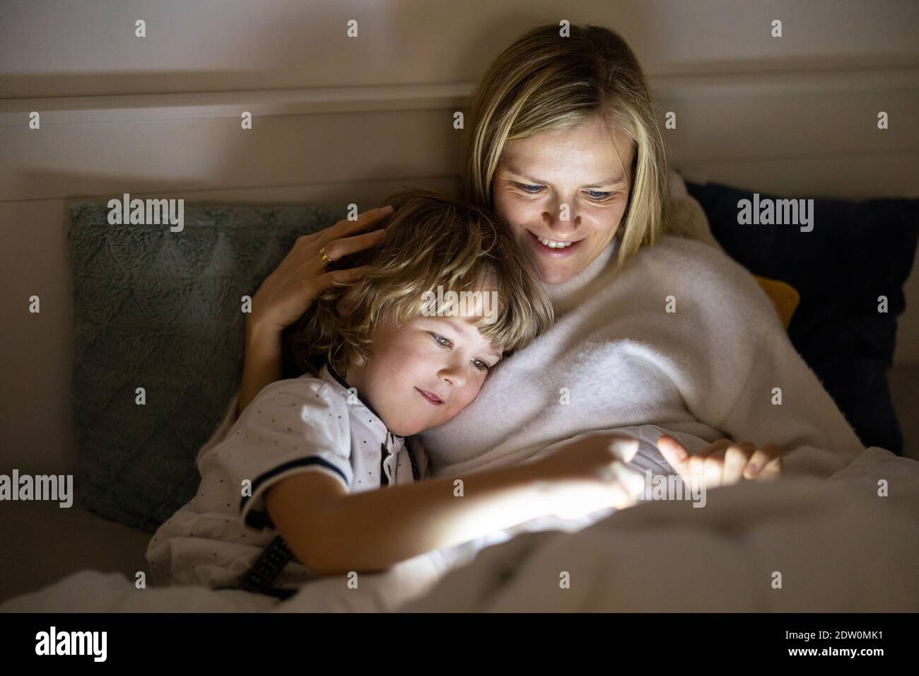 Mutter und Sohn nutzen digitales Tablet zusammen in der Nacht Bett Stockfoto