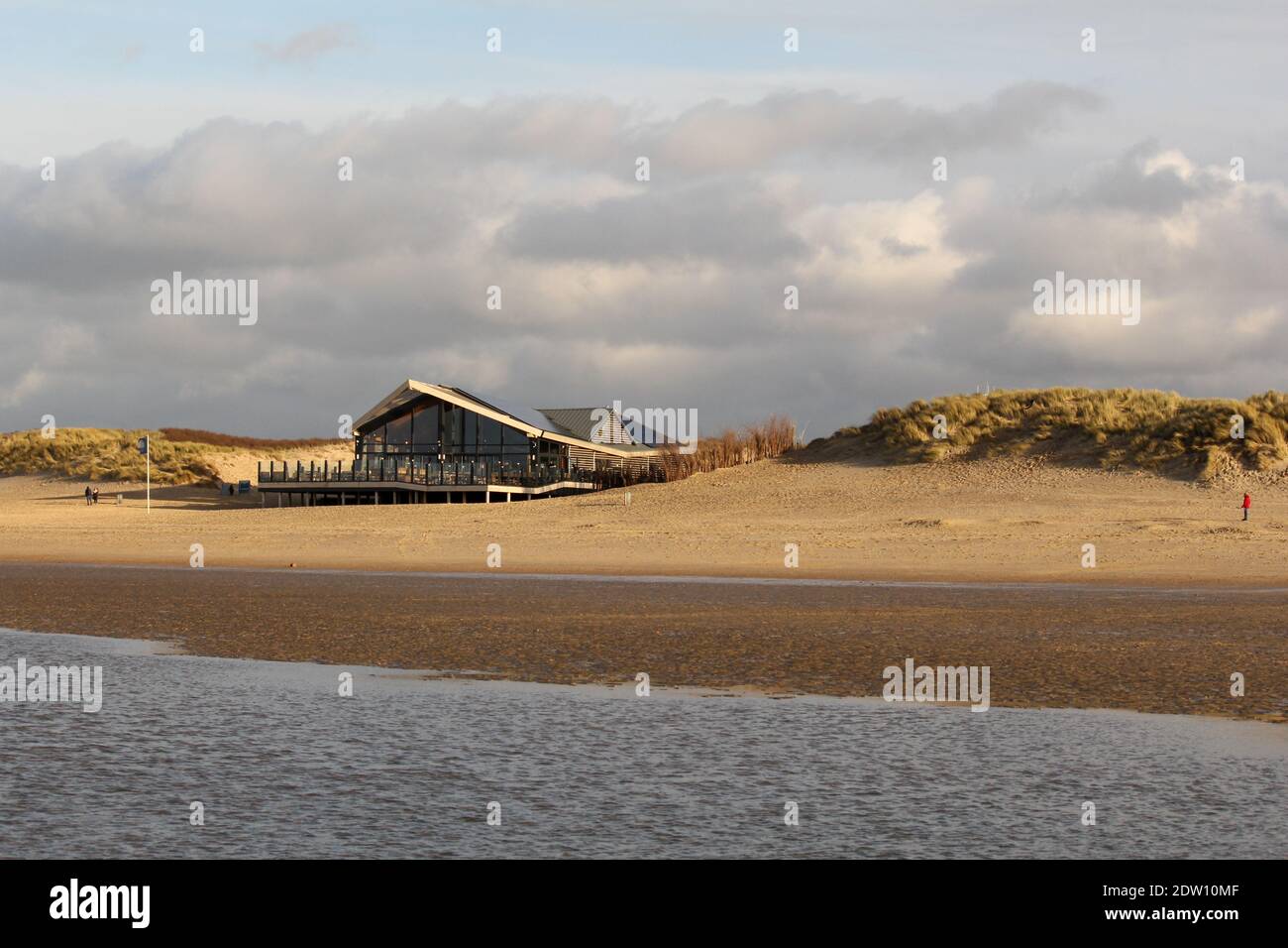Ein moderner Strandpavillon in den Dünen bei den holländern Küste und der Sandstrand und Meer vor und Wolken am Himmel im Winter Stockfoto
