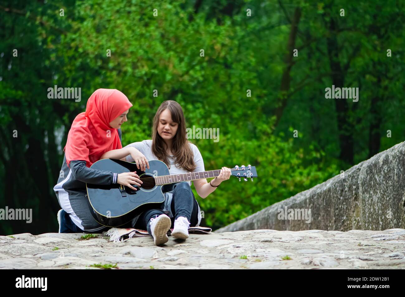 Zwei junge muslimische Mädchen mit Gitarrenunterricht Stockfoto