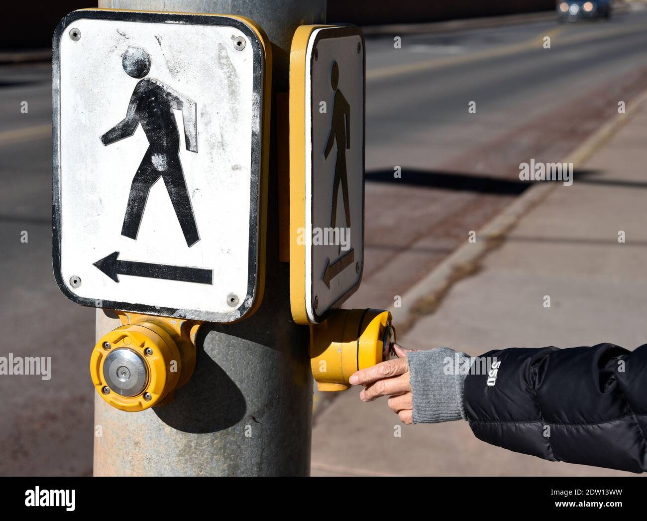 Eine Frau aktiviert ein Fußgängerübergangssignal an einer Kreuzung in Santa Fe, New Mexico. Stockfoto
