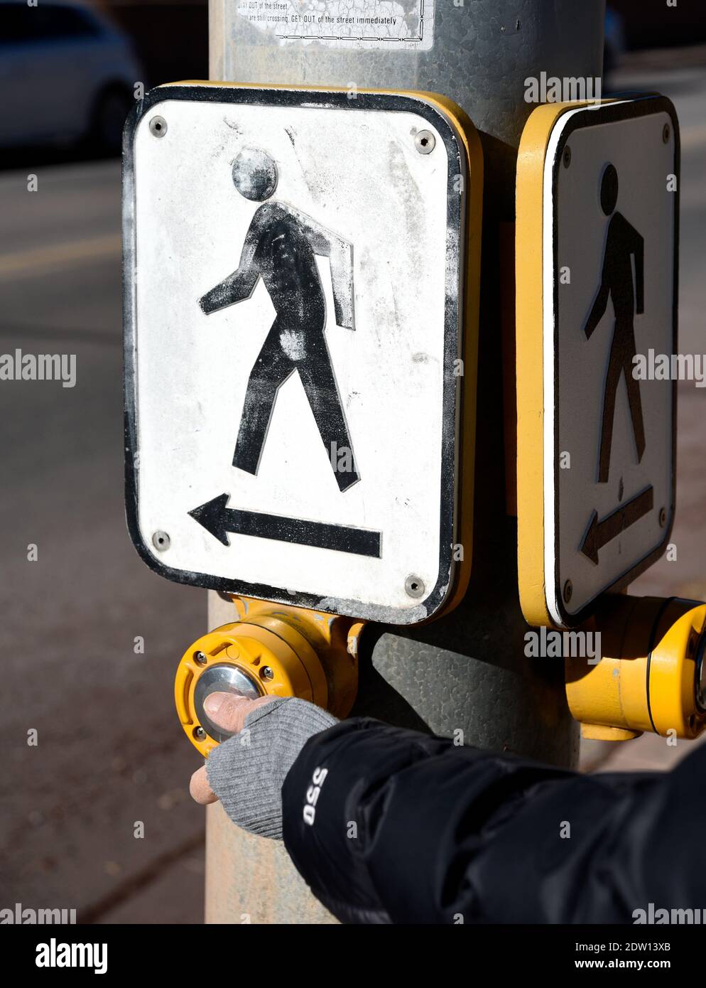 Eine Frau aktiviert ein Fußgängerübergangssignal an einer Kreuzung in Santa Fe, New Mexico. Stockfoto