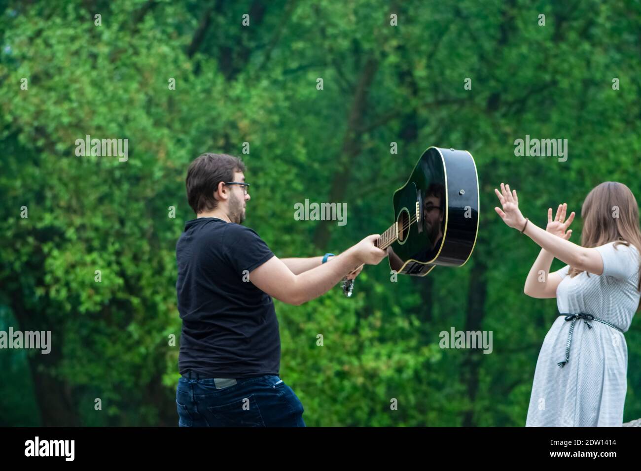 Mann schlägt die Frau mit Gitarre im Freien Stockfoto