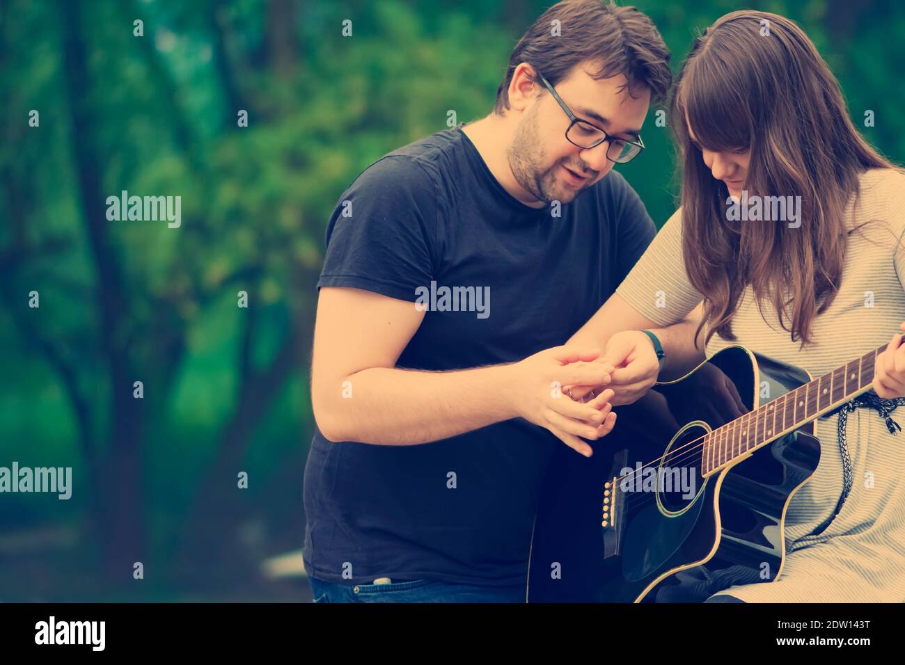 Bruder lehrt Schwester Gitarre in der Natur zu spielen Stockfoto