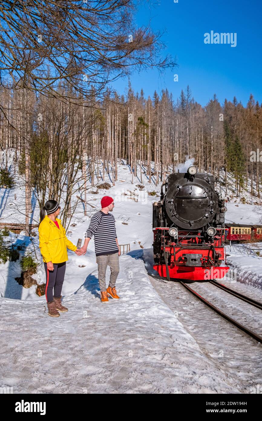 Paar Männer und Frauen wandern im Harz Nationalpark Deutschland, Dampfzug auf dem Weg nach Brocken durch die Winterlandschaft, berühmte Dampfzug durch den Winterberg. Brocken, Harz Deutschland Stockfoto