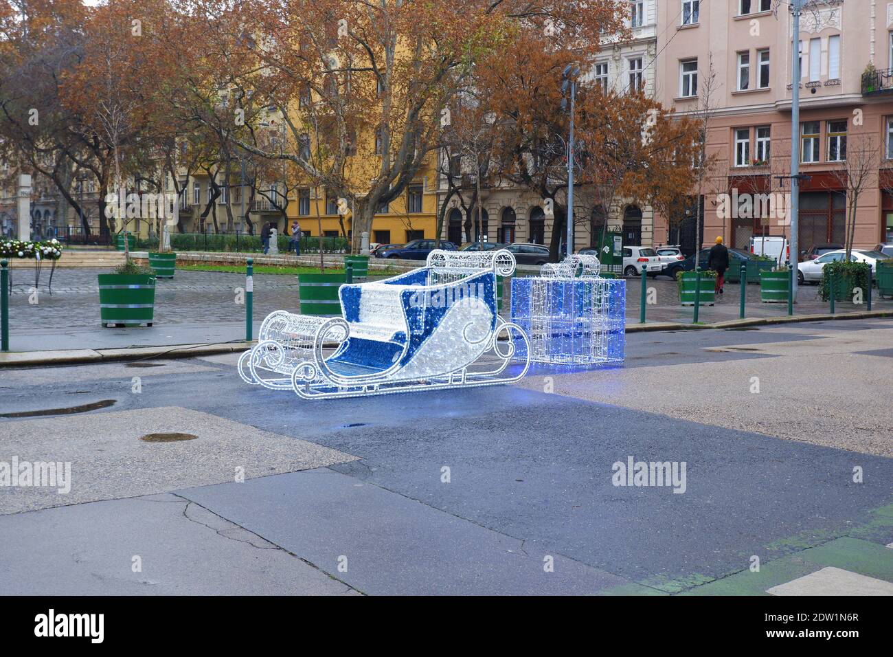 Budapest, Ungarn - 22. Dezember 2020: Beleuchtete Schlitten weihnachtsdekoration mit Geschenkbox auf dem Bakáts Platz Stockfoto