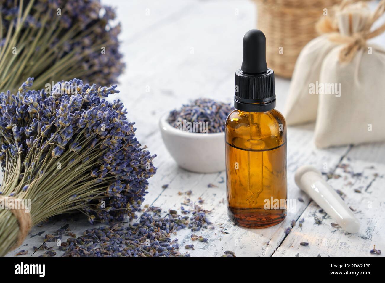 Tropfflasche mit ätherischem Lavendelöl, Beutel und Blumensträuße aus getrockneten Lavendelblüten. Stockfoto