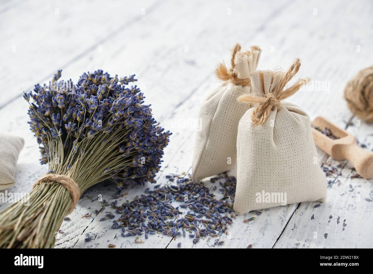 Trockene Lavendelblütensträuße und aromatische Beutel auf weißem Holztisch. Stockfoto