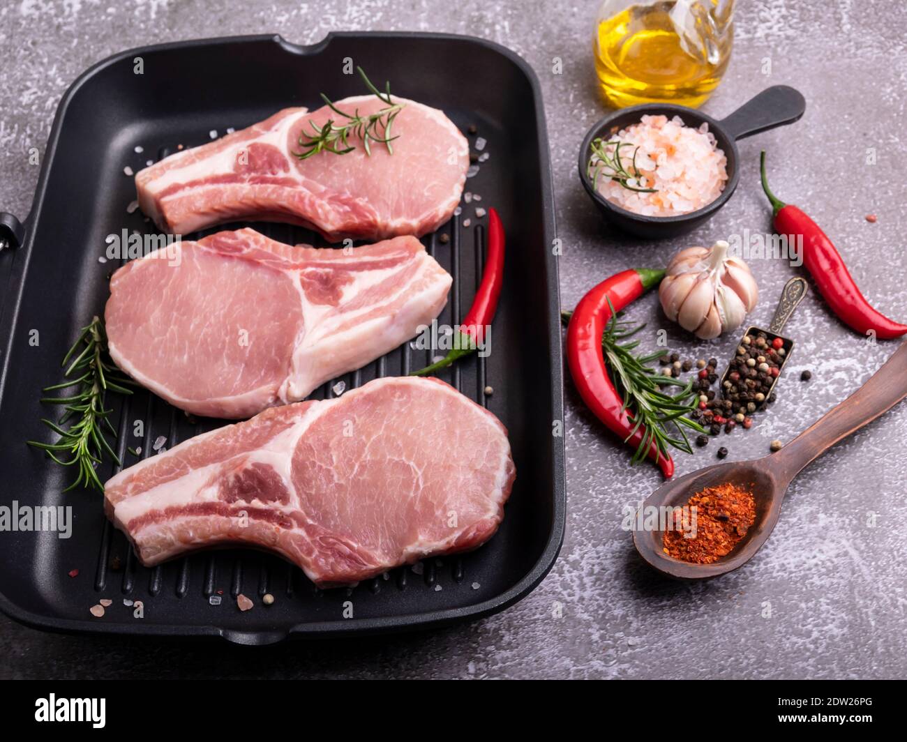 Frisches rohes Fleisch Schweinefleisch, Rindfleisch, auf Knochen hacken, auf Grillpfanne, Gewürze Stockfoto