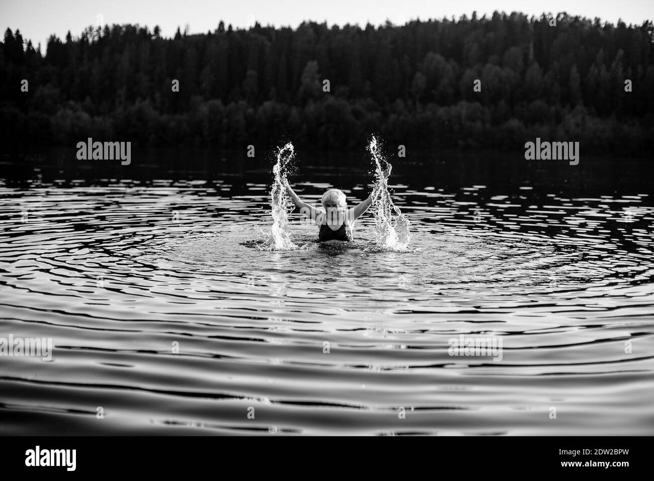 Eine alte Frau, die im Sommerfluss im Dorf planscht. Schwarzweiß-Foto. Stockfoto