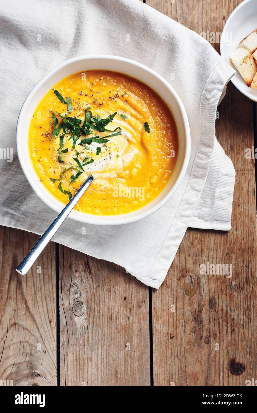 Kürbiscremesuppe mit Kräutern auf rustikalem Holzhintergrund. Stockfoto