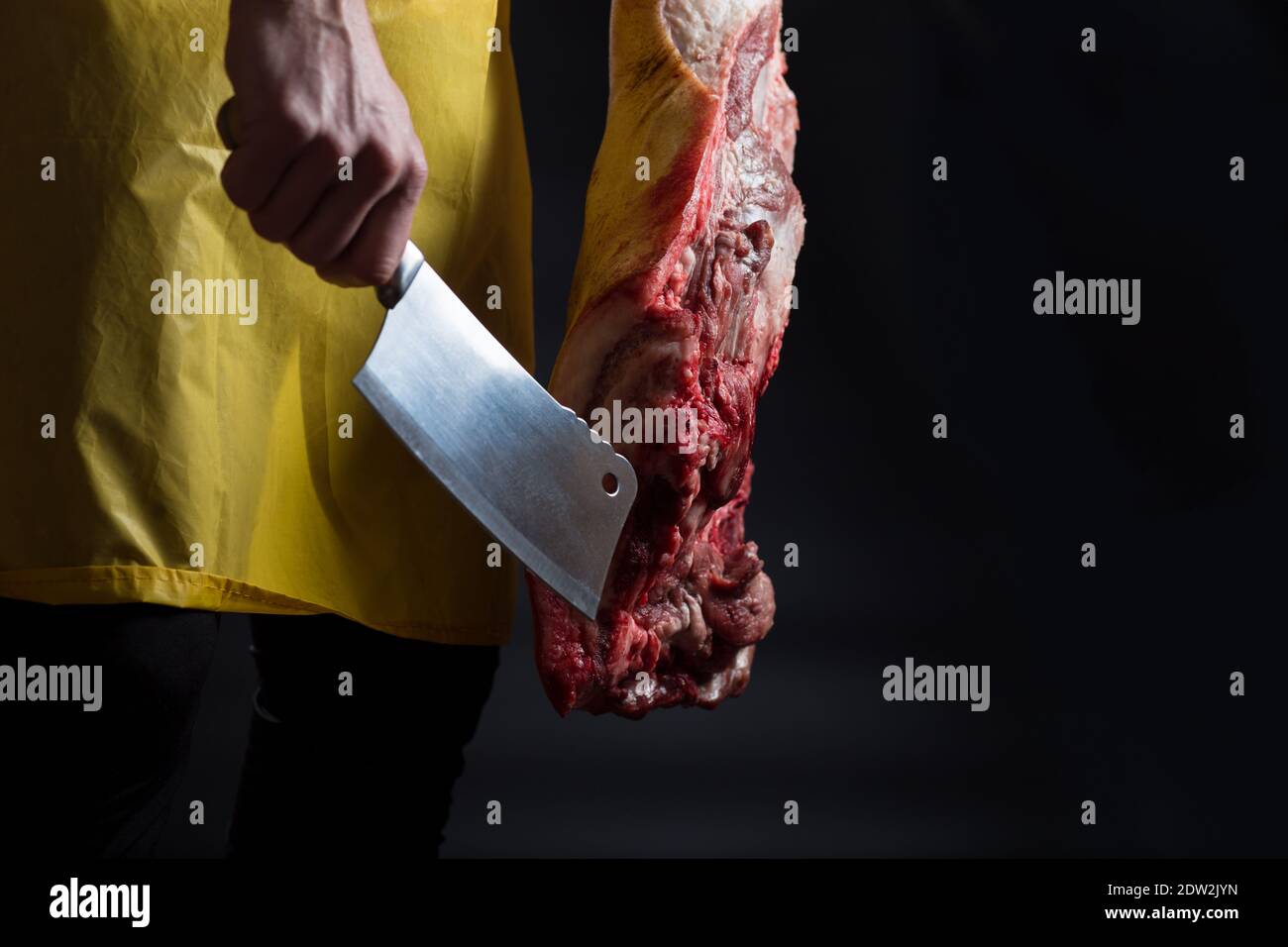 Metzger hält großen Teil von Schweinefleisch und Küche Axt, auf schwarzem Hintergrund mit Copyspace. Stockfoto