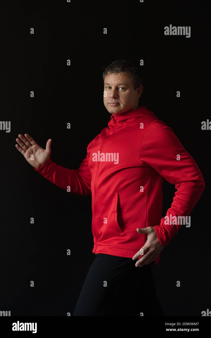 Porträt eines nachdenklichen männlichen Athleten im Alter von 35 bis 45 Jahren in rotem Sportkleid auf schwarzem Hintergrund. Stockfoto