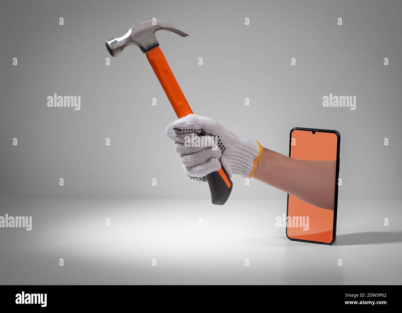 Hand, die einen Hammer aus einem Telefonbildschirm hält Stockfoto