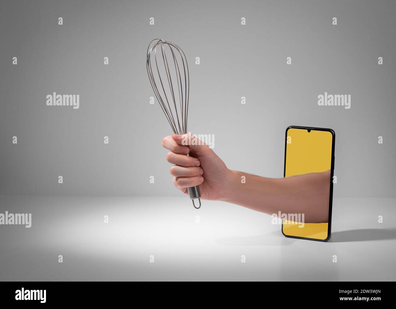 Hand, die einen Metallbesen aus dem Telefon hält Angezeigt Stockfoto