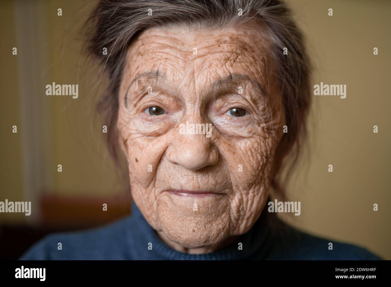 Ältere niedliche Frau von neunzig Jahre alt Kaukasisch mit grauen Haaren und faltigen Gesicht sieht in der Kamera, nette Art Look und lächelt.Reife Großmutter im Ruhestand Stockfoto