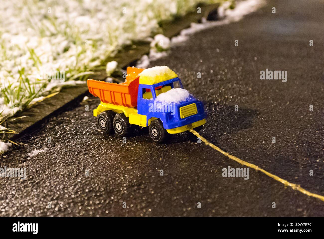 Kinderwagen trägt Schnee. Der Spielzeugtruck ist mit Schnee und Eis bedeckt. Stockfoto