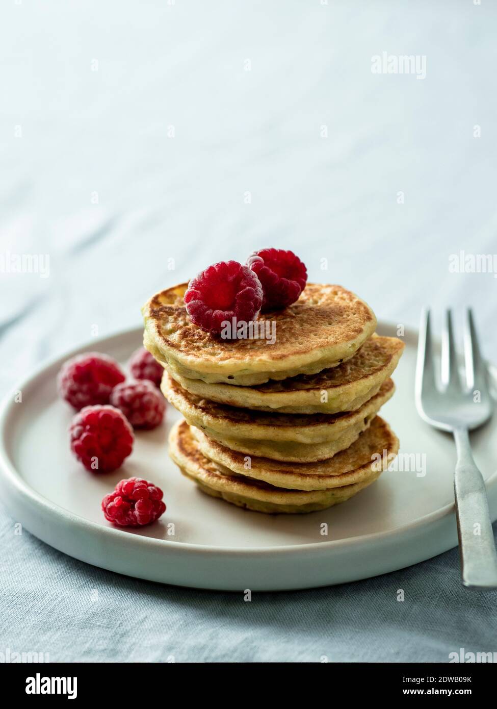 Glutenfreie Zucchini-Pfannkuchen mit Maismehl. Stapel von gesunden Zucchini Pfannkuchen auf Teller über Tischplatte mit blauer Leinentischdecke. Nahaufnahme. Kopie sp Stockfoto