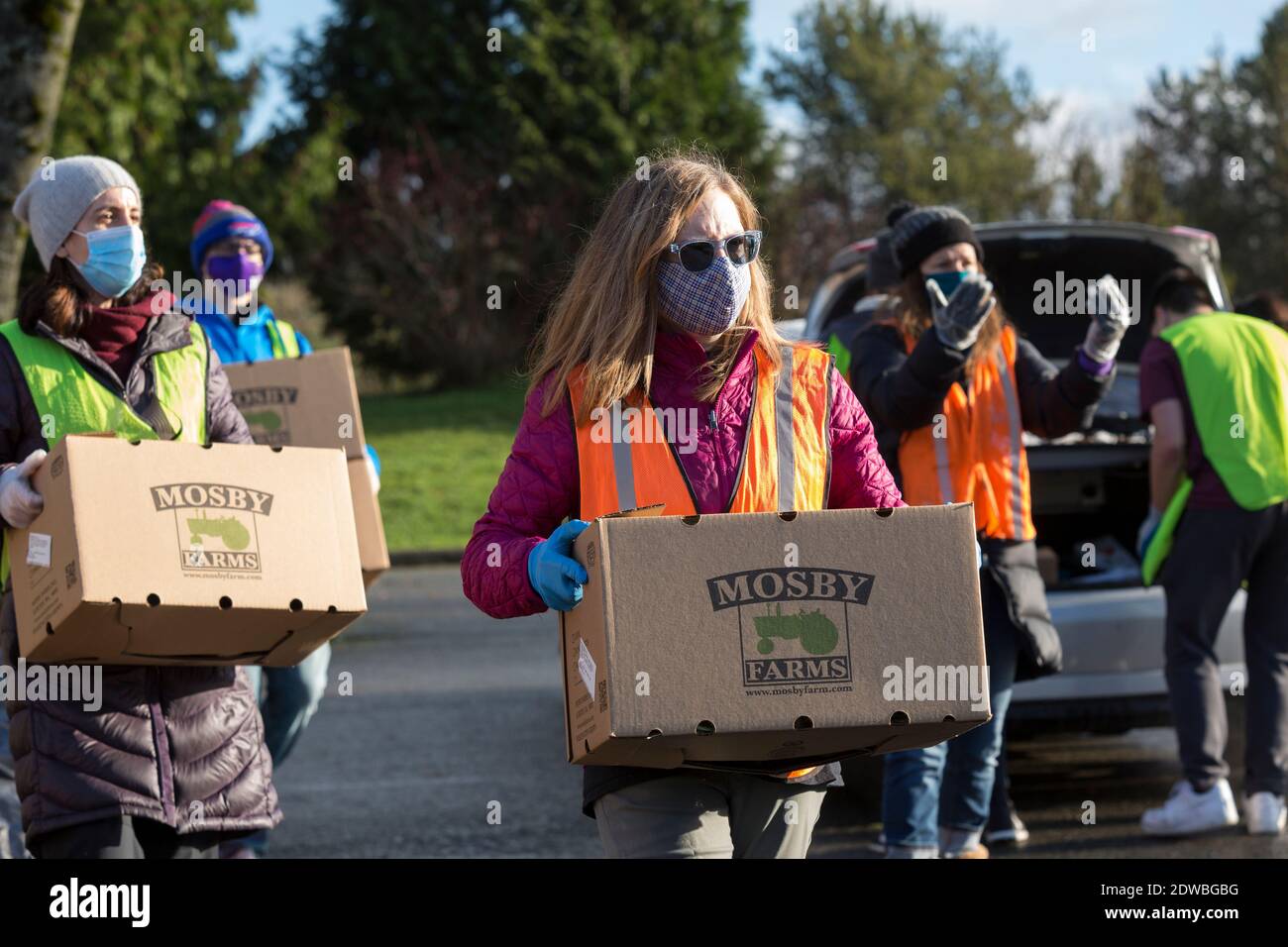 Seattle, Washington, USA. Dezember 2020. Freiwillige laden Notfutterboxen in wartende Fahrzeuge am North Seattle College in Seattle. Food Lifeline förderte die laufende Verteilung der Bevölkerung, da sich die Zahl der lebensmittelunsicheren Menschen im Staat Washington im Gefolge der Covid-19-Pandemie verdoppelte. Quelle: Paul Christian Gordon/Alamy Live News Stockfoto