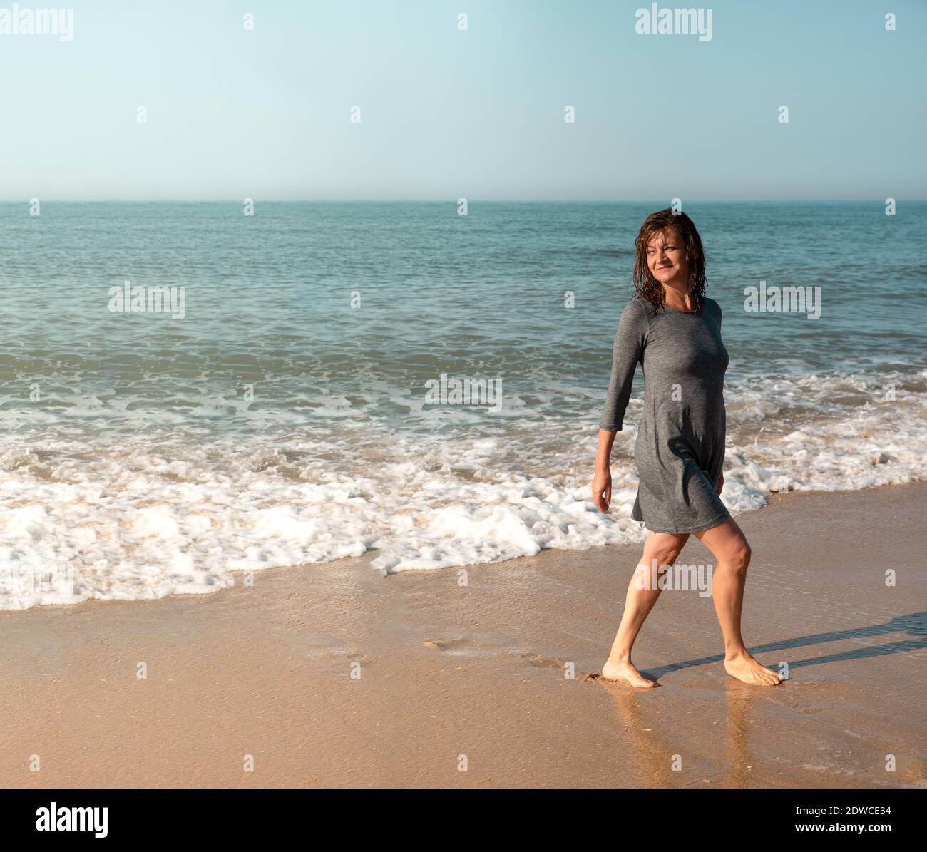 Frau, die am Strand entlang geht und zurückschaut Stockfoto