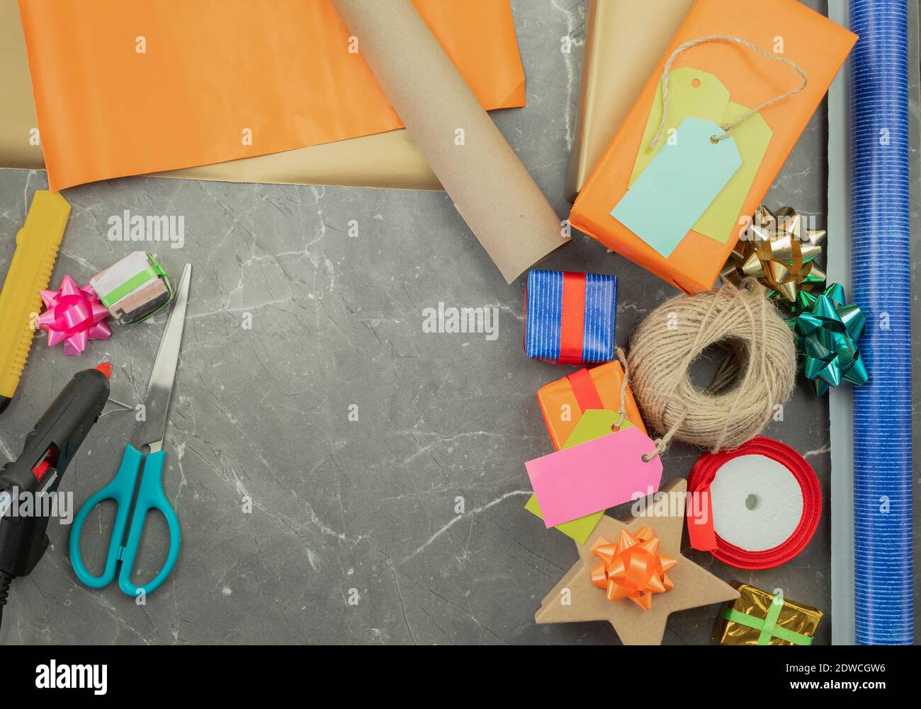 Geschenkverpackung mit Händen in Geschenkpapier auf dem Tisch als Hintergrund. Geburtstag oder Jubiläum Geschenke Einpacken in Geschenkpapier, Draufsicht Stockfoto