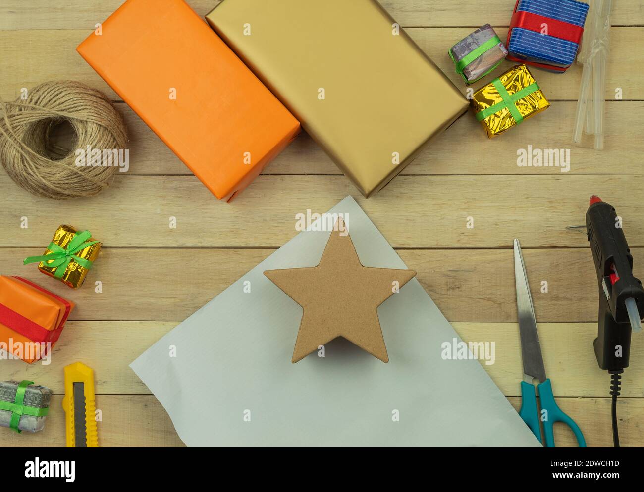 Geschenkverpackung mit Händen in Geschenkpapier auf dem Tisch als Hintergrund. Geburtstag oder Jubiläum Geschenke Einpacken in Geschenkpapier, Draufsicht Stockfoto
