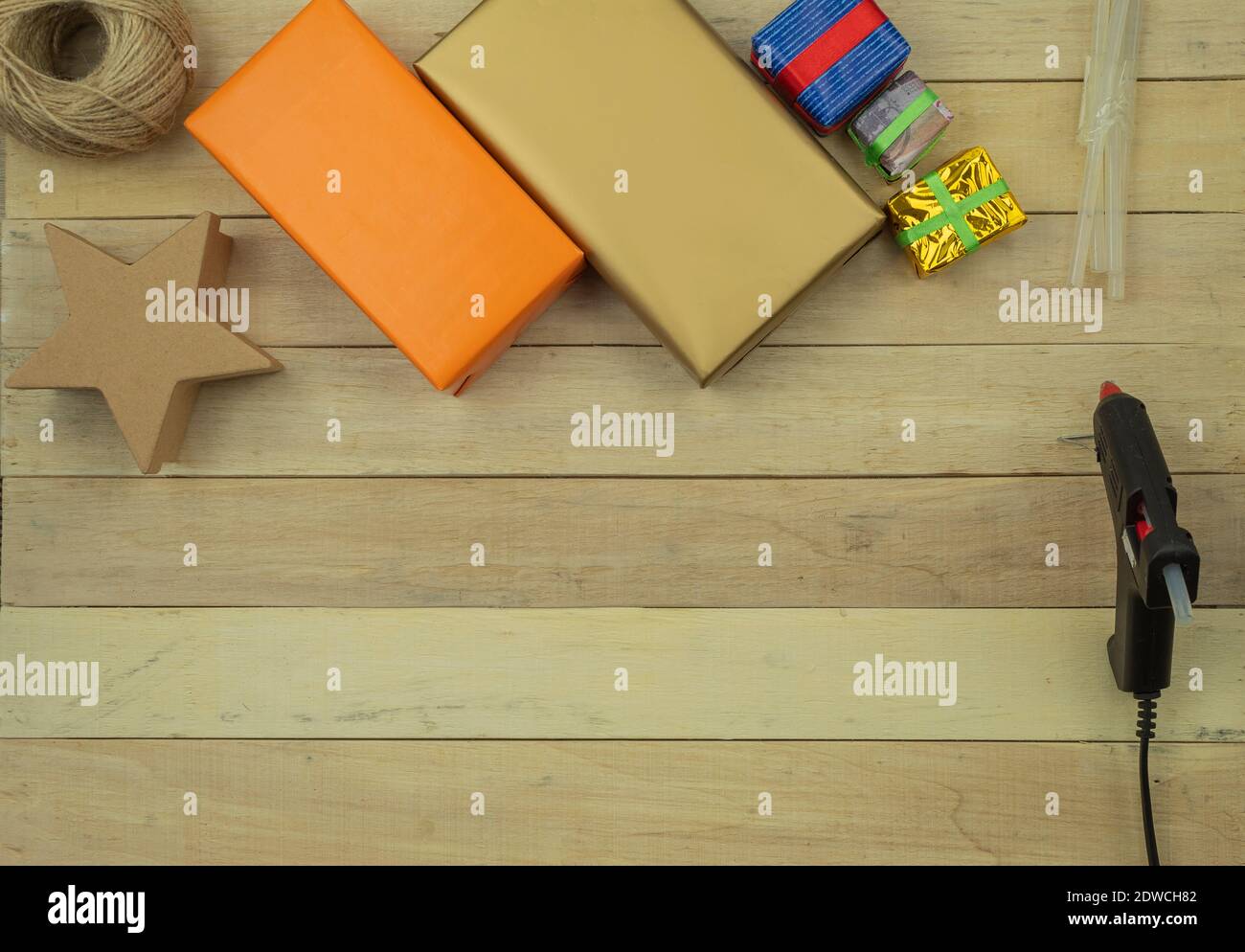 Geschenkverpackung mit Händen in Geschenkpapier auf dem Tisch als Hintergrund. Geburtstag oder Jubiläum Geschenke Einpacken in Geschenkpapier, Draufsicht Stockfoto