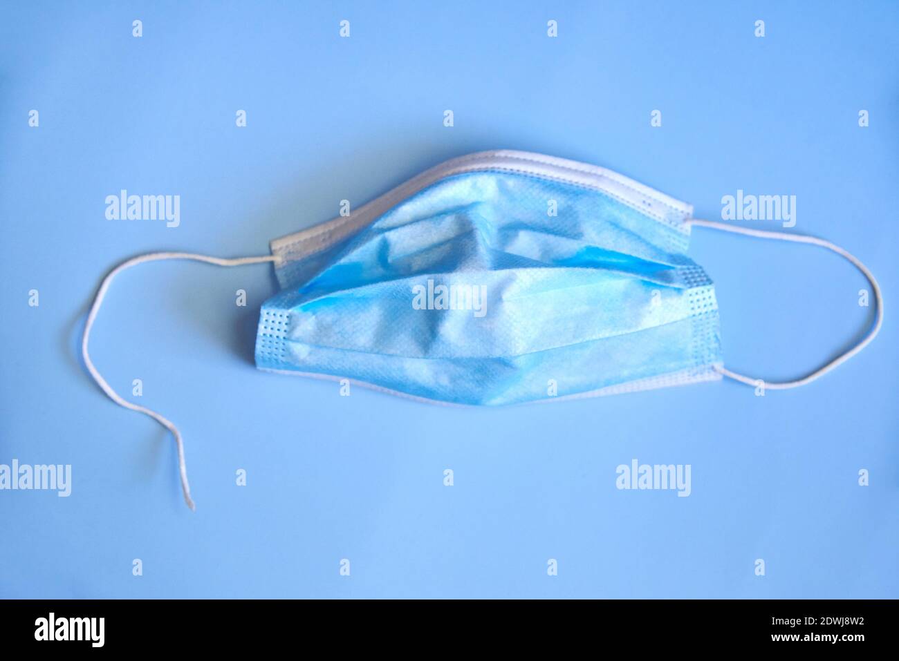 Zerrissene medizinische Maske auf blauem Hintergrund, das Konzept der Viruserkrankungen, Coronavirus. Stockfoto