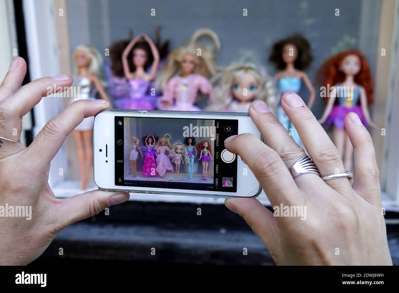 Die Frau macht ein Foto-Handy von einer Sammlung von Puppen, Schnappschuss Stockfoto