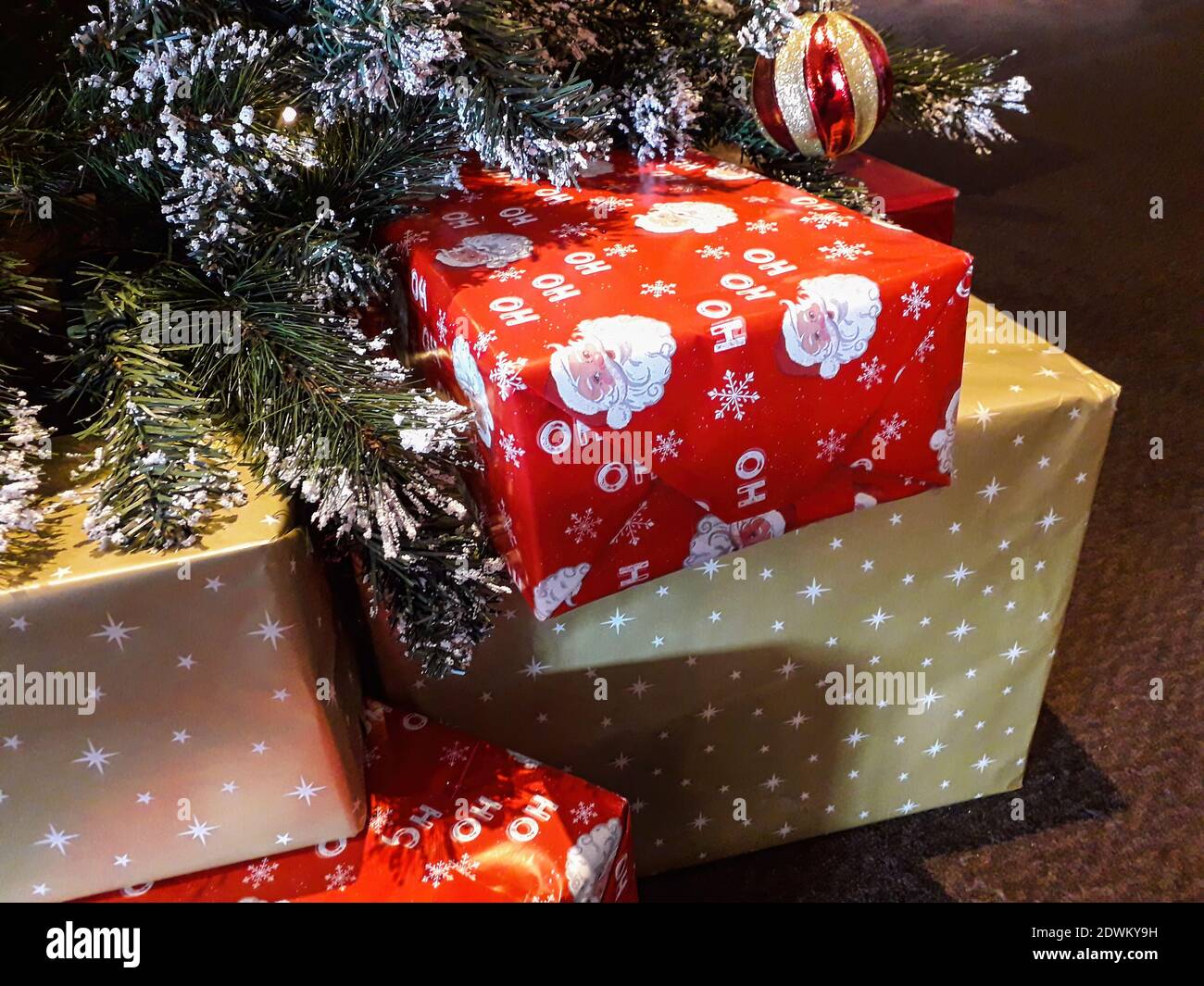 Weihnachtsgeschenke eingewickelt in rot und Gold Papier unter einem Weihnachtsbaum, der von Vater Santa Claus zu verlassen war Am zweiten Weihnachtsfeiertag geöffnet sein Stockfoto