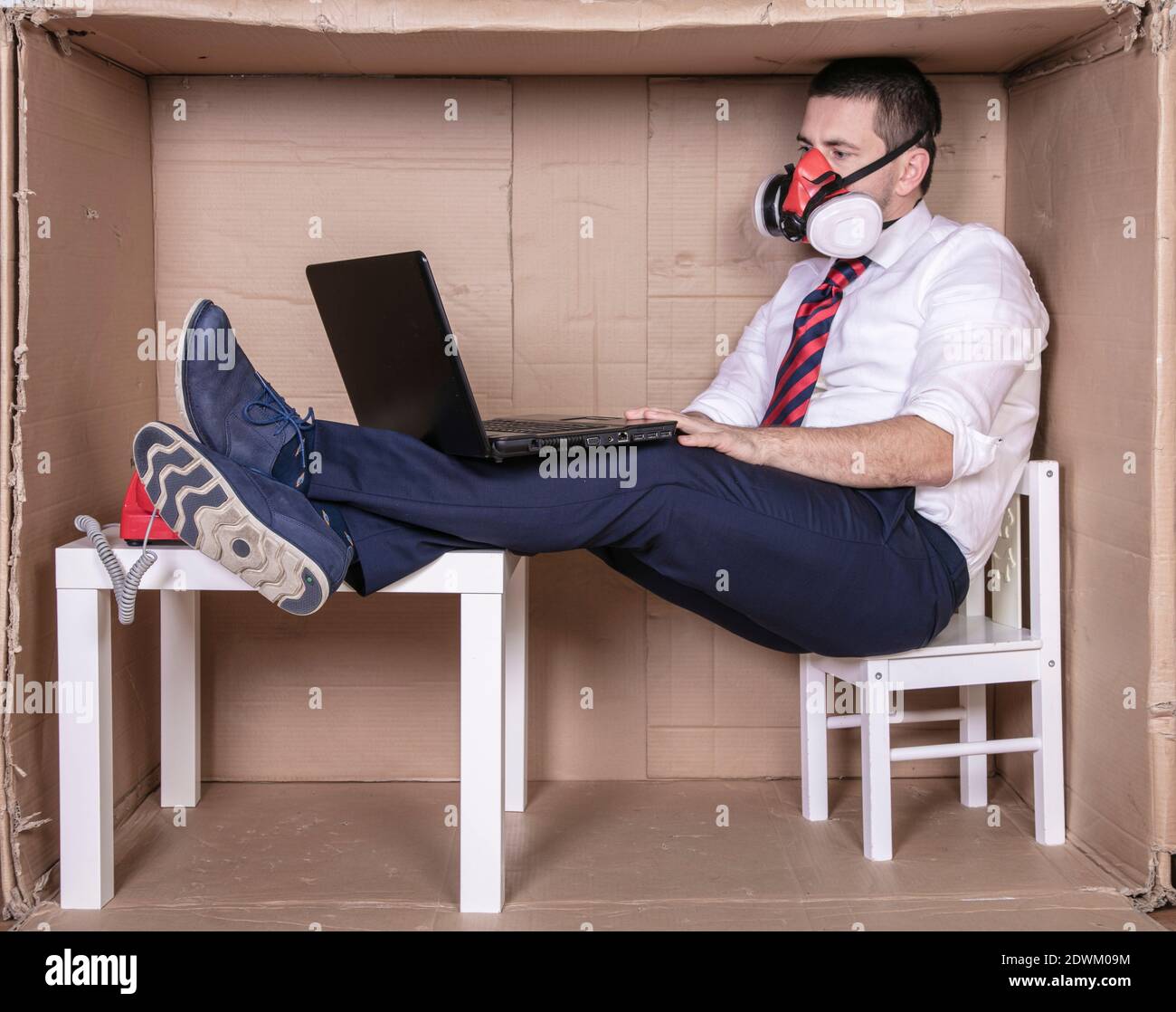 Geschäftsmann mit Laptop auf dem Schoß arbeiten hart in seinem Kleines, beenges Büro Stockfoto