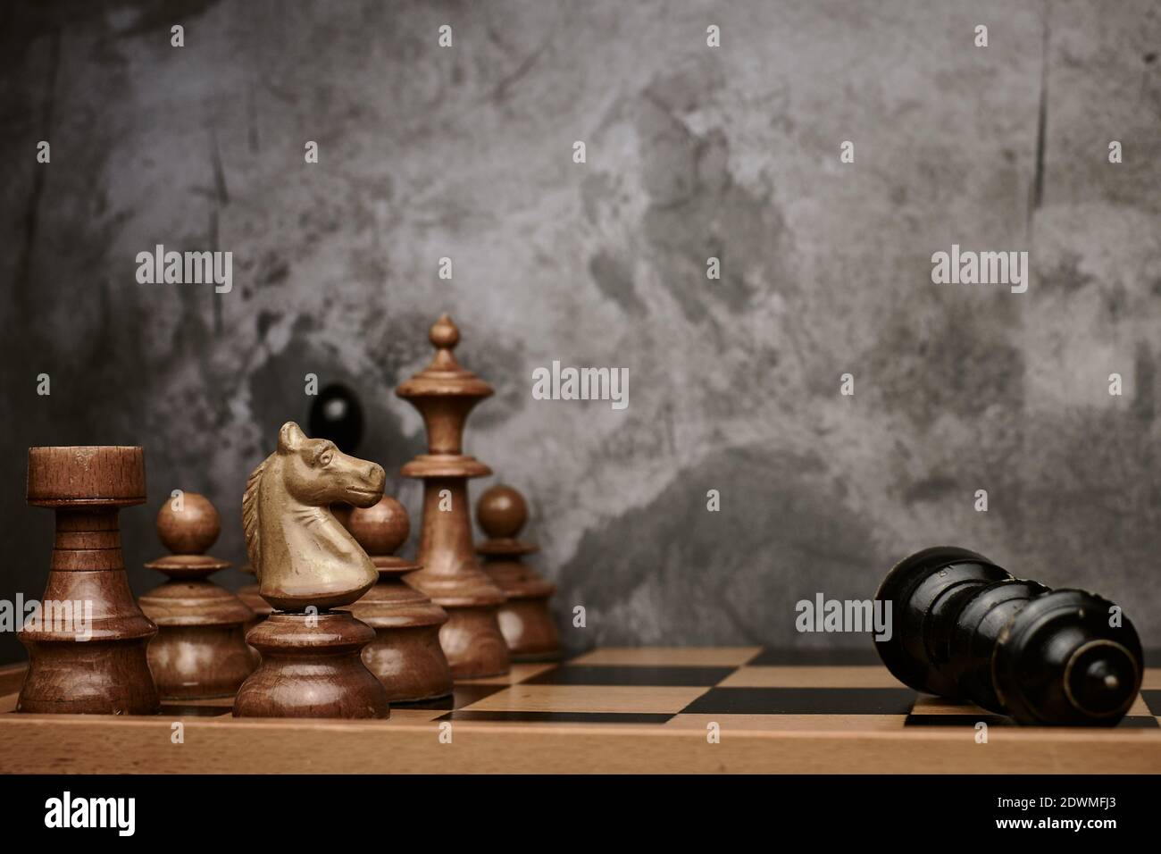 Schachfiguren besiegen den schwarzen König auf dem Schachbrett mit Grau Hintergrund Stockfoto