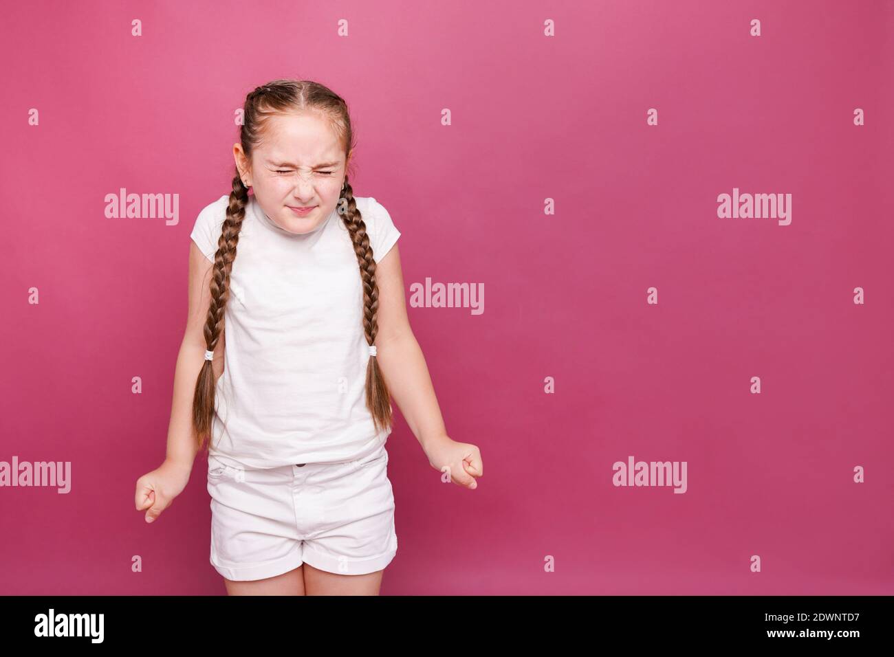 Nette 7-8 Jahre altes Mädchen runzelte die Stirn mit geschlossenen Augen auf Rosa Hintergrund Stockfoto