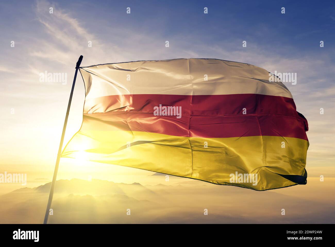 Südossetien Flagge winkt auf der Oberseite Sonnenaufgang Nebel Stockfoto