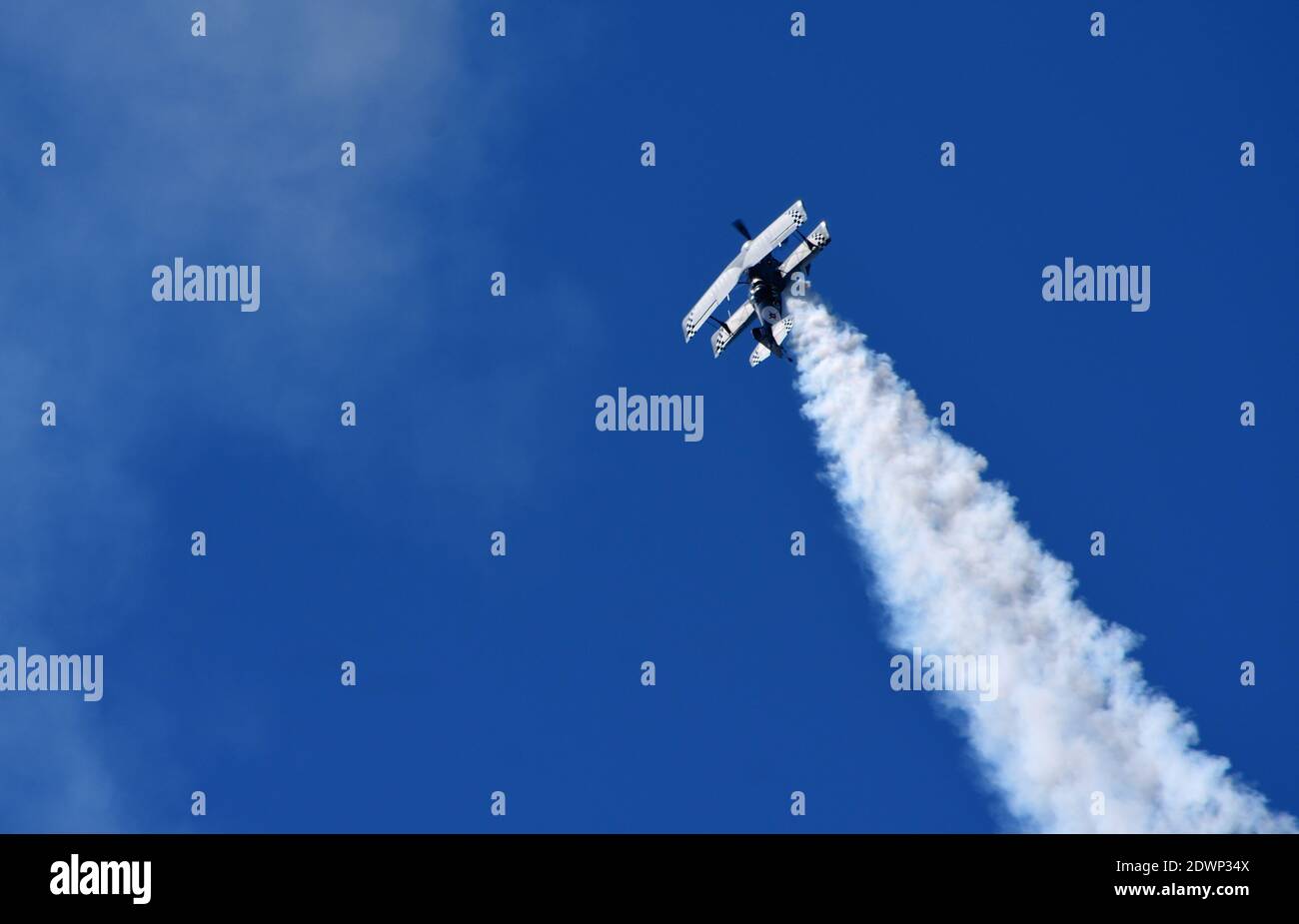 Pitts Modell 12 Stunt-Flugzeug mit Rauchspur und blauem Himmel. Stockfoto