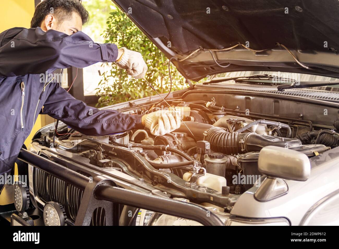Autoreparaturarbeiter tragen dunkelblaue Uniformen ziehen den Ölstandsanzeiger des Autos, um in der Kfz-Reparatur-Service-Center zu überprüfen, Automobilindustrie und gara Stockfoto