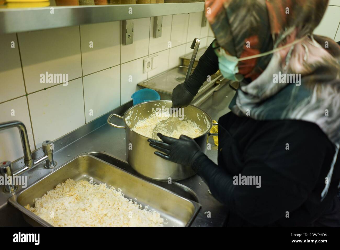 Berlin, Deutschland. Dezember 2020. Beim Kalthilfeprojekt im Kreuzberger Himmel werden warme Speisen portioniert. Mitglieder des Flüchtlingsnetzwerks "Be an Angel e. V.' kochen 450 warme Mahlzeiten am Tag. Gleichzeitig werden 450 Lunchpakete zubereitet. Die 900 Portionen werden jeden Mittag an soziale Einrichtungen in der ganzen Stadt geliefert, wo sie an Obdachlose verteilt werden. Das Land Berlin fördert das Hilfsprojekt bis März 2021. Quelle: Jörg Carstensen/dpa/Alamy Live News Stockfoto