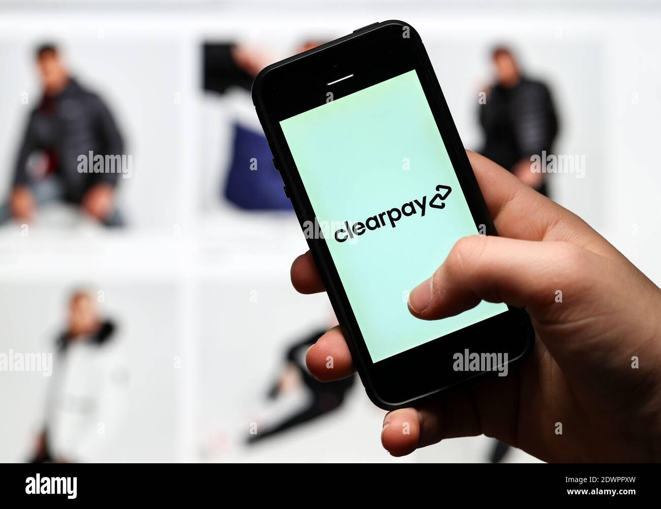 Ein Mann, der online einkauft und mit der Clearpay App auf seinem Handy bezahlt. Stockfoto