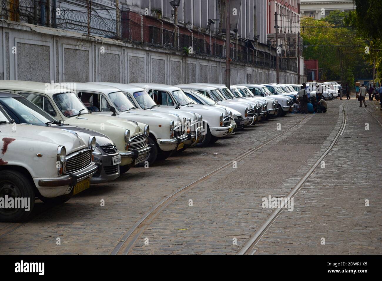 Kalkutta, Indien - März 2014: Reihe alter alter alter alter weißer Ambassador-Taxis entlang der Straßenbahnschienen in Kalkutta. Oldtimer in Reihe. Stockfoto