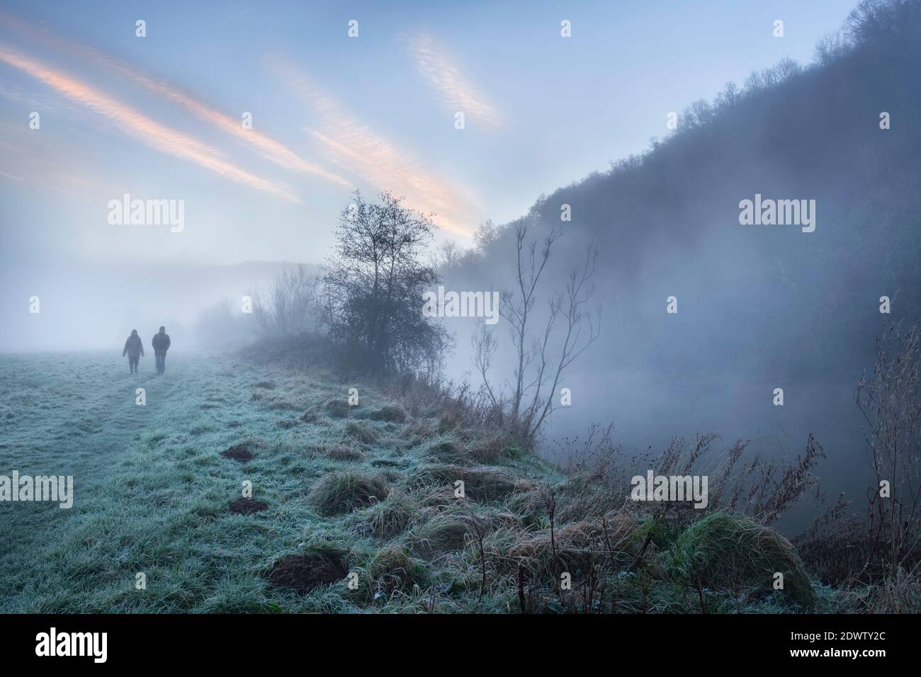 Zwei Menschen, die an einem nebligen Morgen am Brockweir entlang des Flusses Wye spazieren. Stockfoto