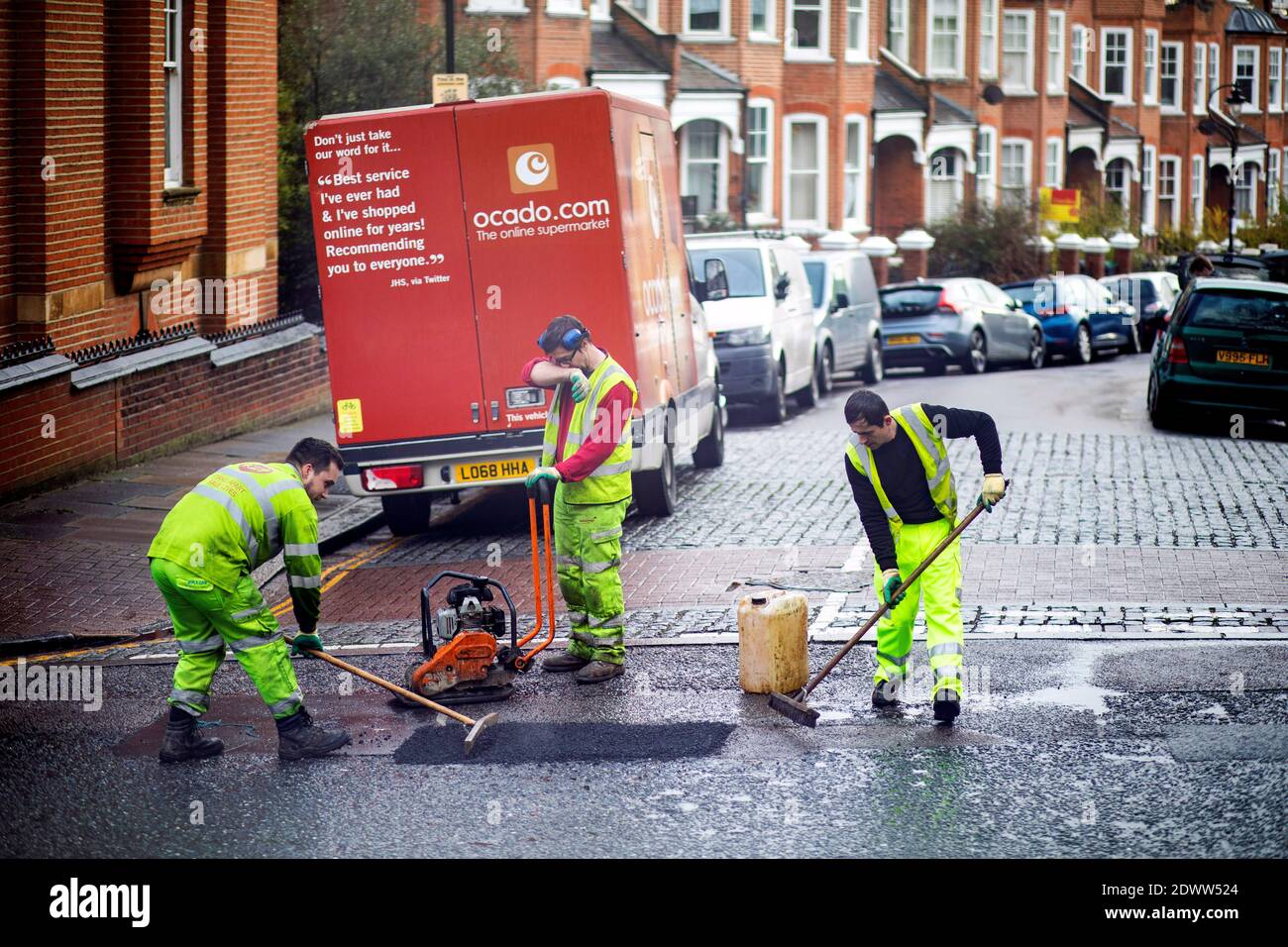 Bild zeigt: Team von Straßenarbeitern, die ein Schlagloch in der Straße in Highgate North London füllen Bild von Gavin Rodgers/ Pixel8000 Stockfoto