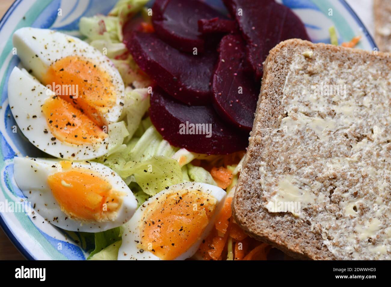 Ein farbenfrohes, leichtes Mittagessen mit gekochtem Ei, Krautsalat, Salat und Rote Bete mit hausgemachtem Vollkornbrot. Stockfoto