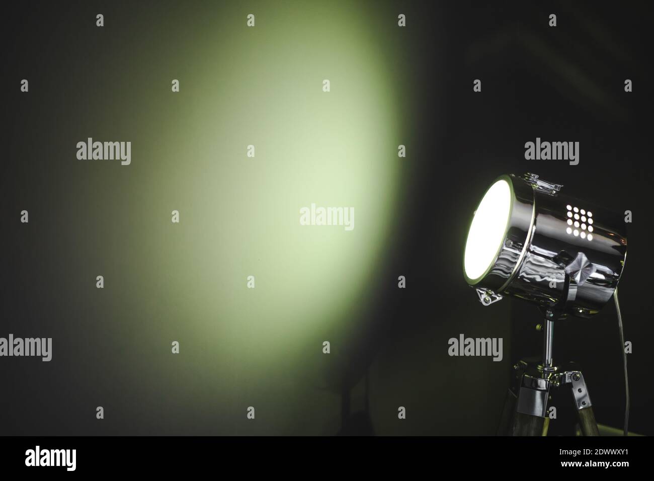 Hellgrüne Spotlight-Lampe an einer dunklen Wand mit Platz Zum Kopieren Stockfoto