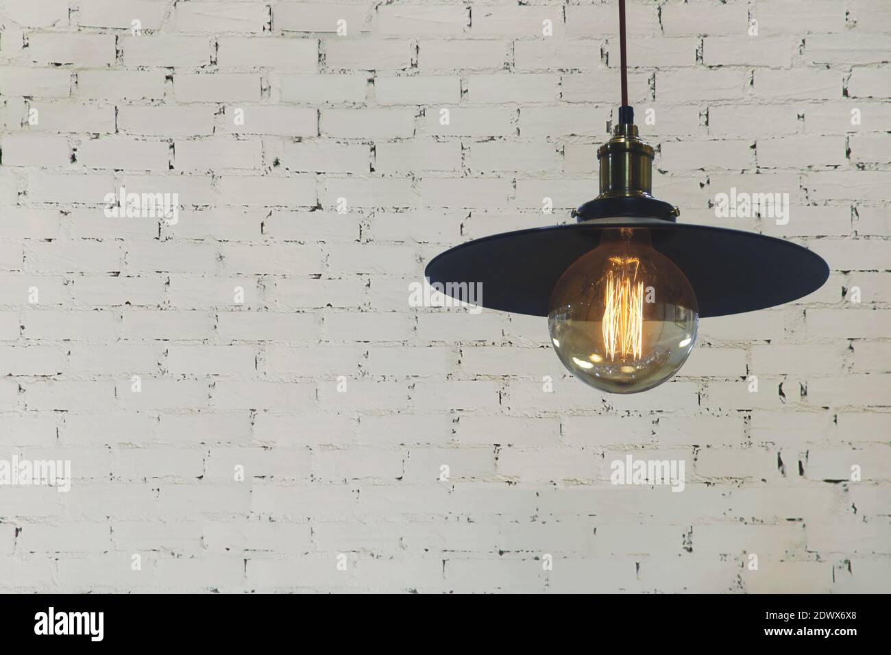 Industrial Style Licht Anhänger mit dekorativen Edison Glühbirne auf Weiße Ziegelwand Hintergrund Stockfoto