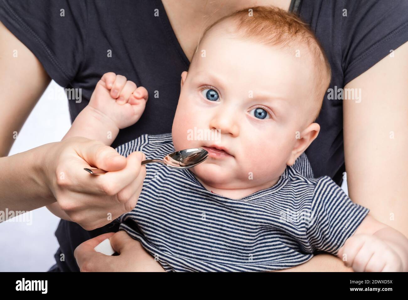 Mutter Fütterung Baby Junge mit Vitamin oder flüssige Medizin mit Löffel Stockfoto